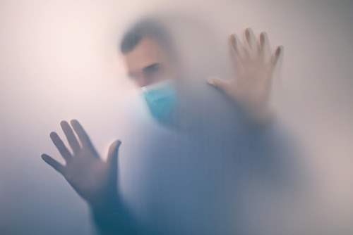 man behind wall in disposable face mask