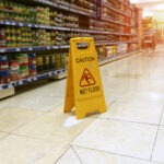 A yellow “caution wet floor” sign sits in a grocery store aisle.
