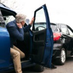 Elder man and young man get out of cars after an accident.