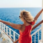 Woman smiling beside cruise ship railing with ocean horizon in background