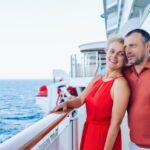 married couple standing together on cruise ship deck overlooking ocean