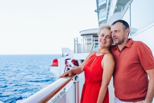 married couple standing together on cruise ship deck overlooking ocean