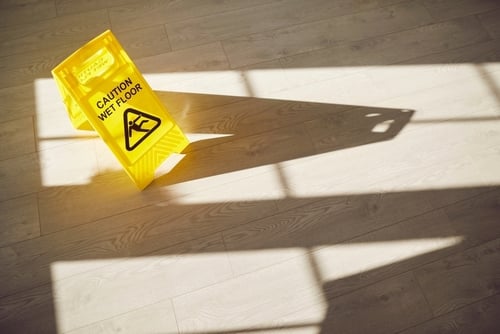 Caution Wet Floor sign tipped over on indoor hardwood floor