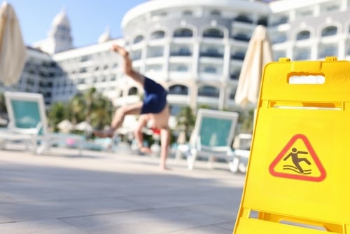 wet floor caution sign with person falling on slippery surface nearby