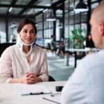 injured woman wearing neck brace meeting with professional across office desk