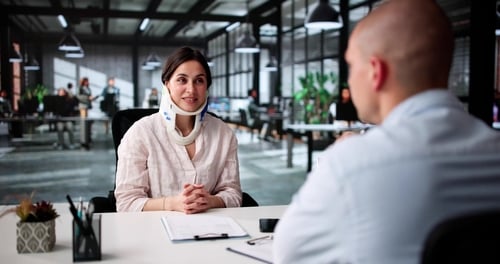injured woman wearing neck brace meeting with professional across office desk