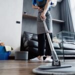 Housekeeper wiping kitchen countertop with spray bottle and cloth during home cleaning