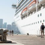 passengers walking along dock beside large cruise ship moored at port