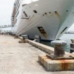 large cruise ship docked at port with passengers walking along pier