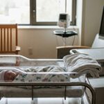 newborn infant resting in hospital bassinet beside medical monitoring equipment