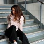 woman sitting on metal staircase steps with handbag beside her