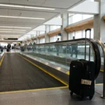 rolling suitcase with luggage tag beside airport moving walkway terminal