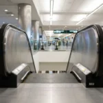 escalator entry point inside large public airport terminal with directional signage