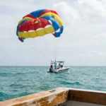 parasail canopy towed by motorboat with passengers over open ocean waters
