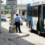 FLL Airport Shuttle bus stopped at terminal curb near uniformed worker