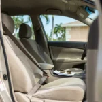 open car door revealing front seat with seatbelt, sunglasses, and document on console